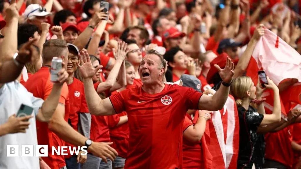 Fans celebrating in red attire during a match Fans celebrating in red attire during a match