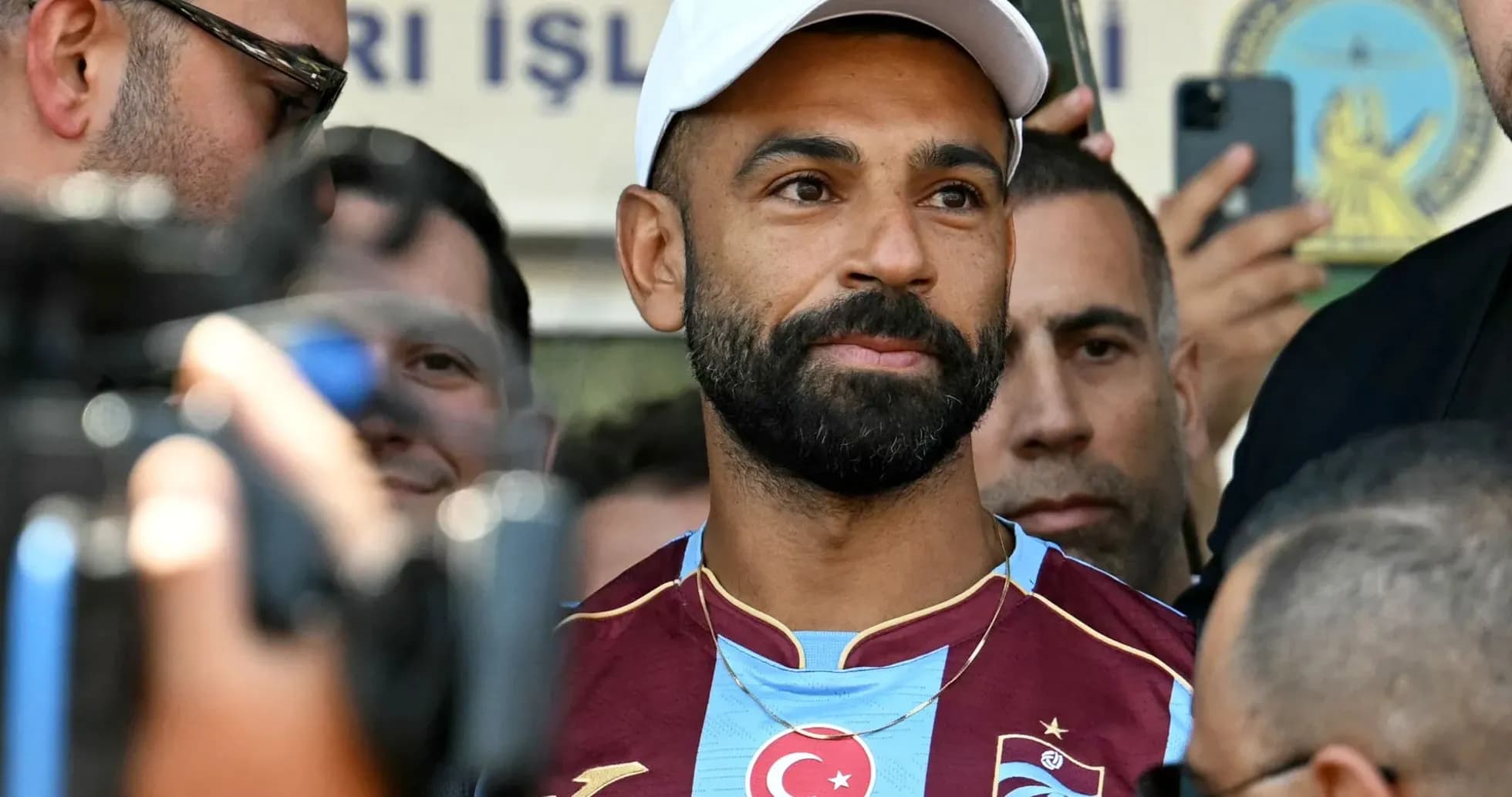 Player in Trabzonspor jersey surrounded by fans and media Player in Trabzonspor jersey surrounded by fans and media