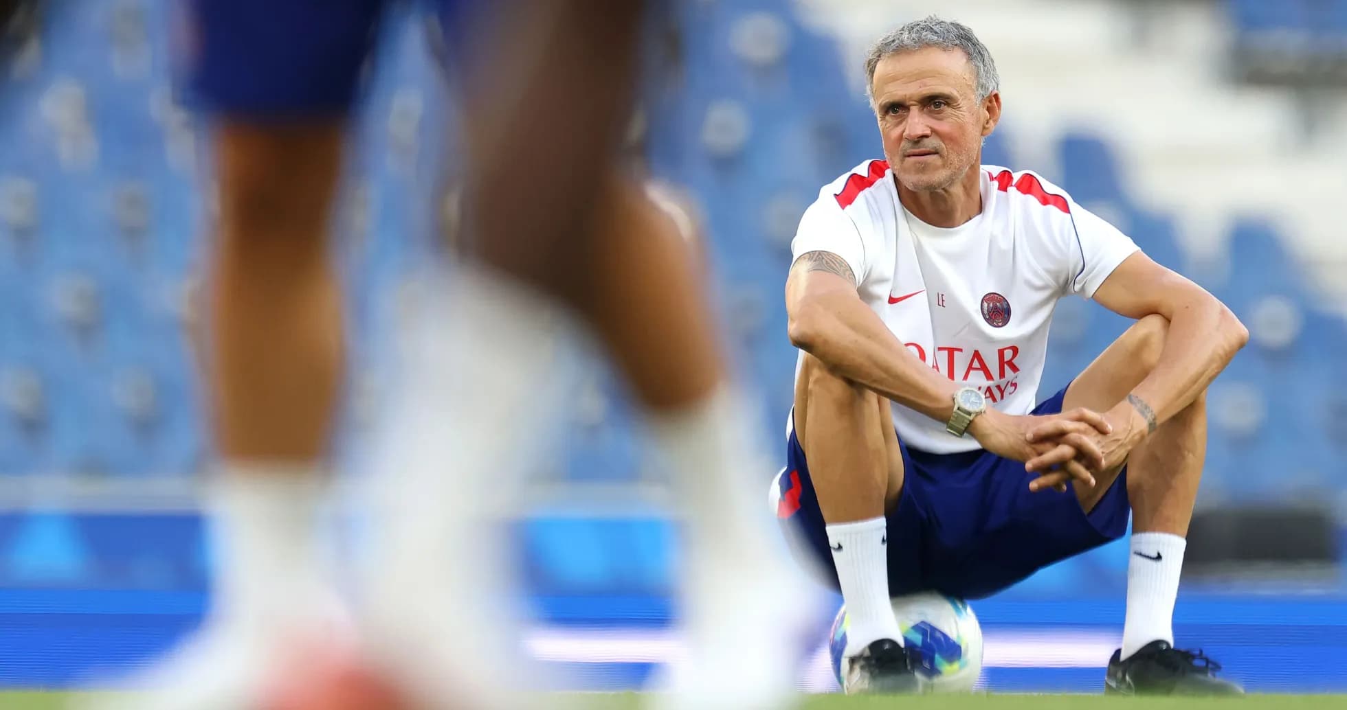 Coach squatting on training pitch observing players Coach squatting on training pitch observing players