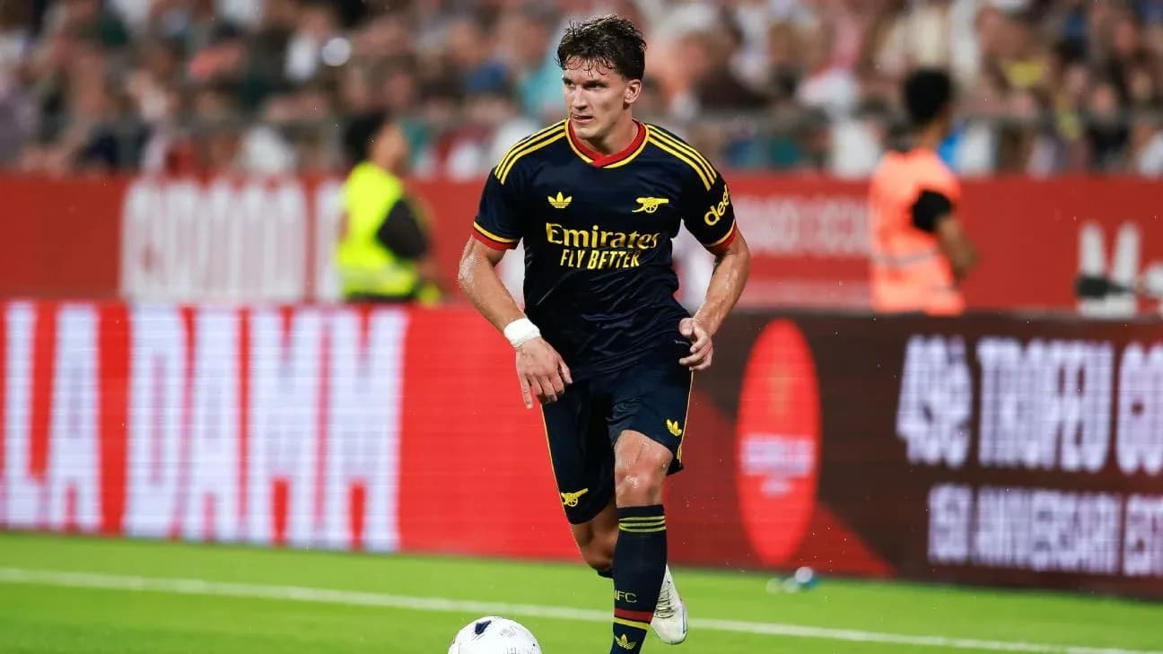 Player in Arsenal kit dribbling the ball on field Player in Arsenal kit dribbling the ball on field