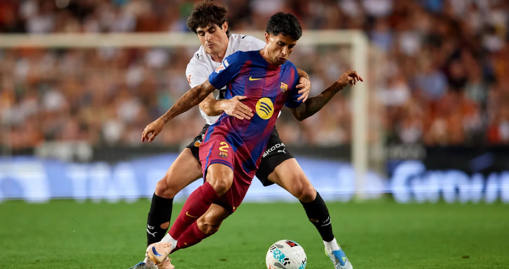 Barcelona player challenged by Valencia defender during match Barcelona player challenged by Valencia defender during match