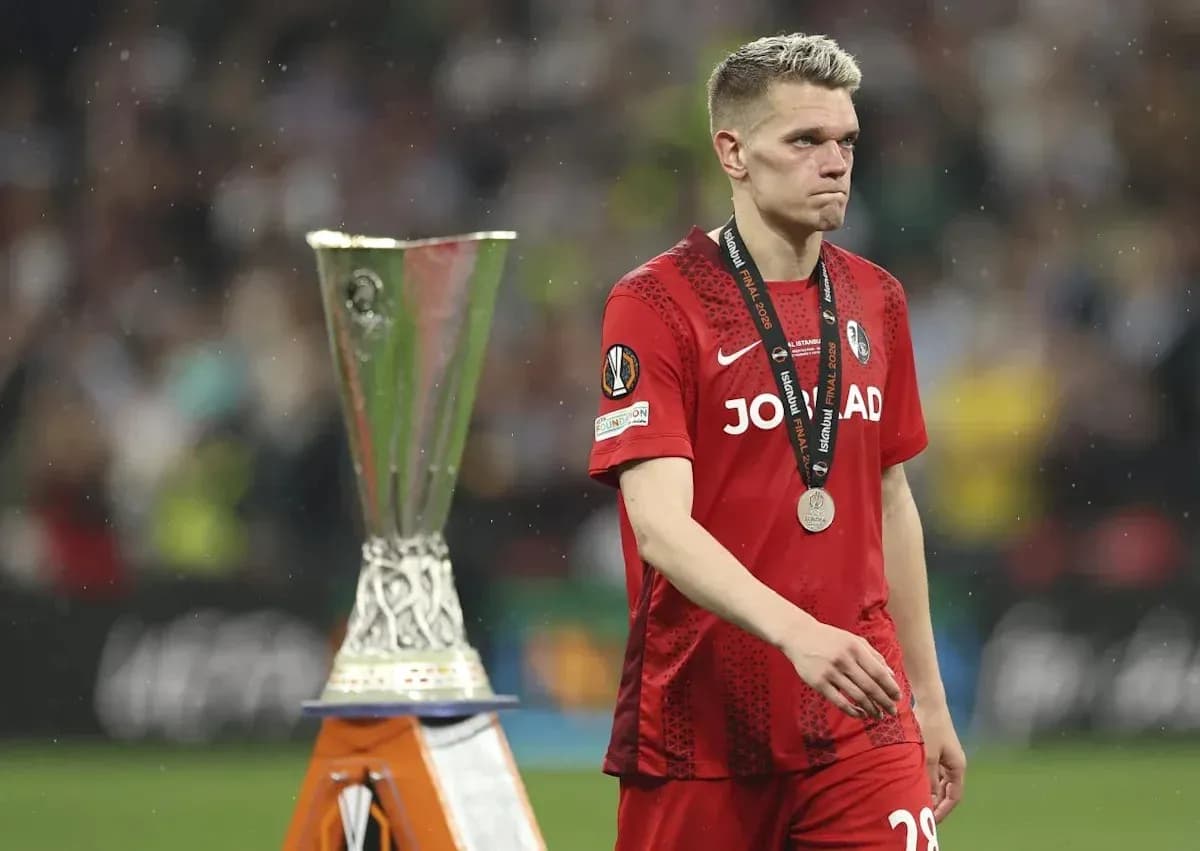 Player in red jersey walking past trophy with medal Player in red jersey walking past trophy with medal