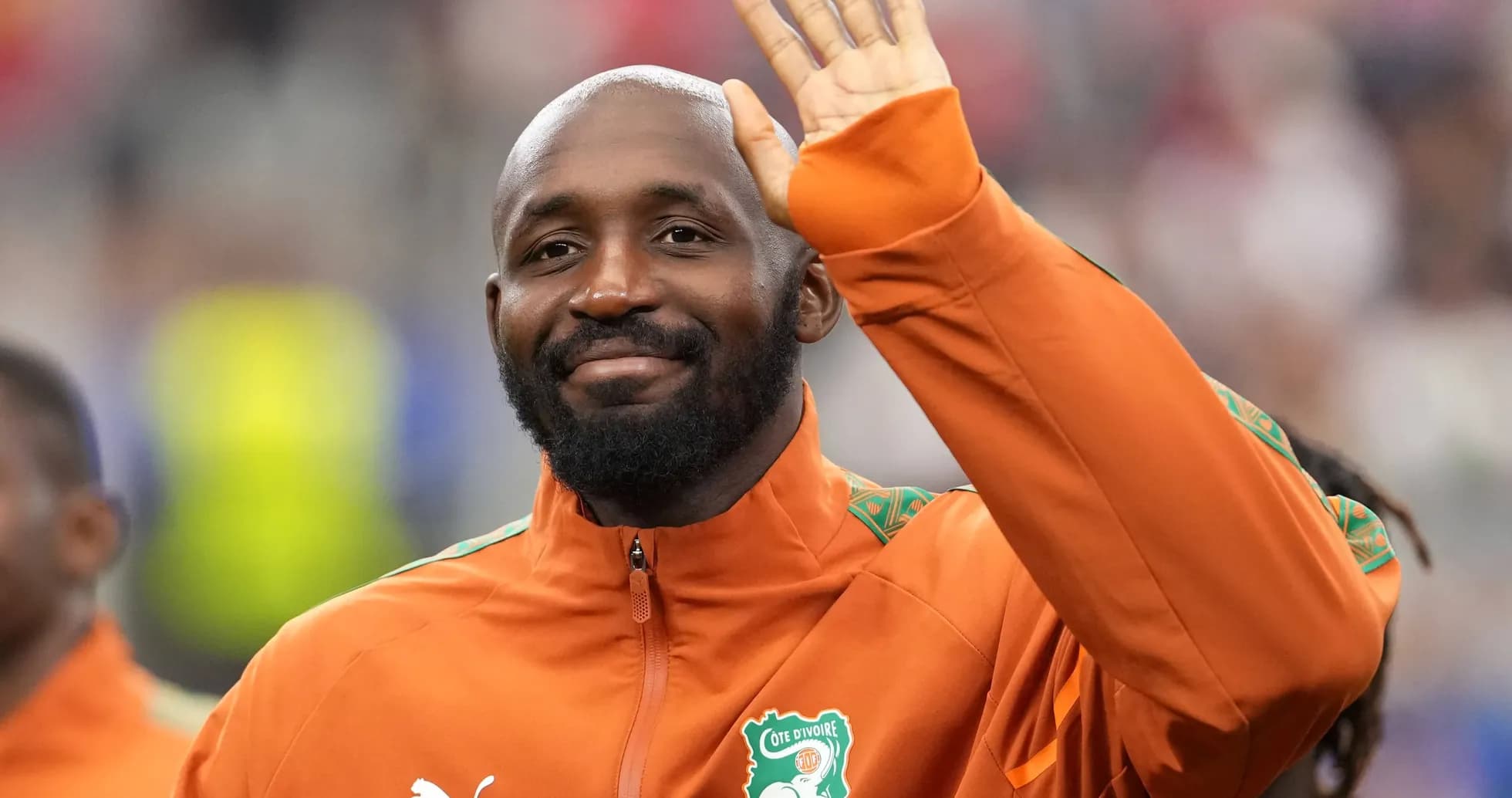 Player waving while wearing Cote d'Ivoire jacket Player waving while wearing Cote d'Ivoire jacket