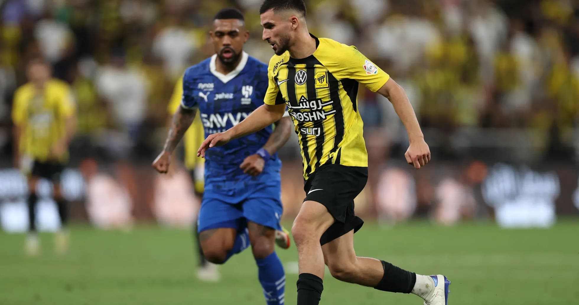 Player in yellow jersey dribbling past opponent in blue Player in yellow jersey dribbling past opponent in blue