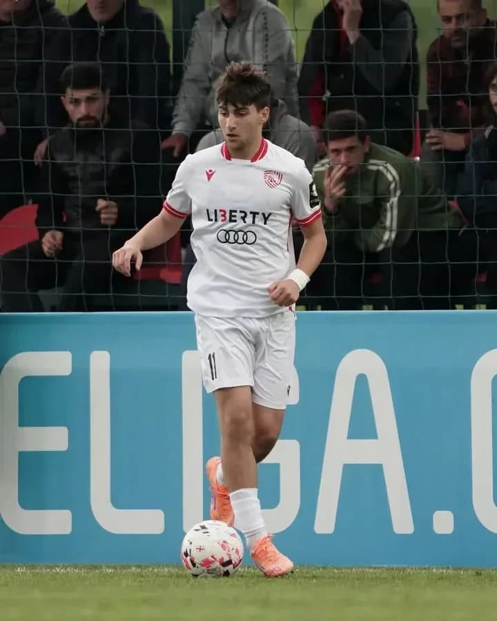 Player in white kit dribbling soccer ball on field Player in white kit dribbling soccer ball on field