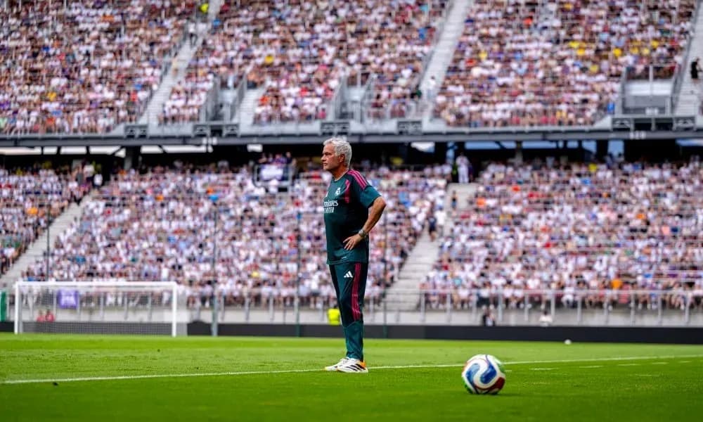 Coach observing match in front of packed stadium Coach observing match in front of packed stadium