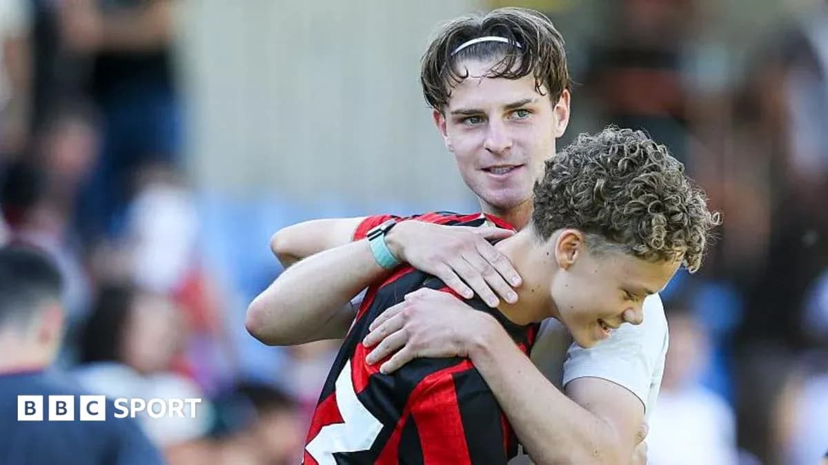 Two players embracing on the pitch after match Two players embracing on the pitch after match