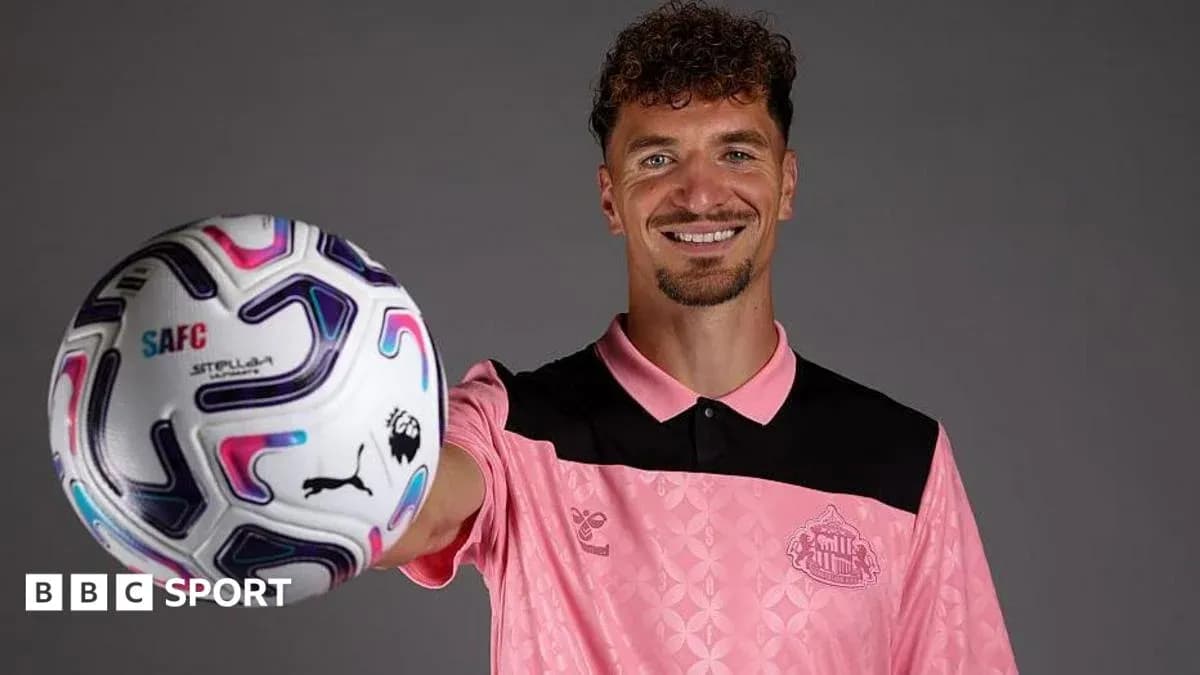Player holding a football while smiling Player holding a football while smiling