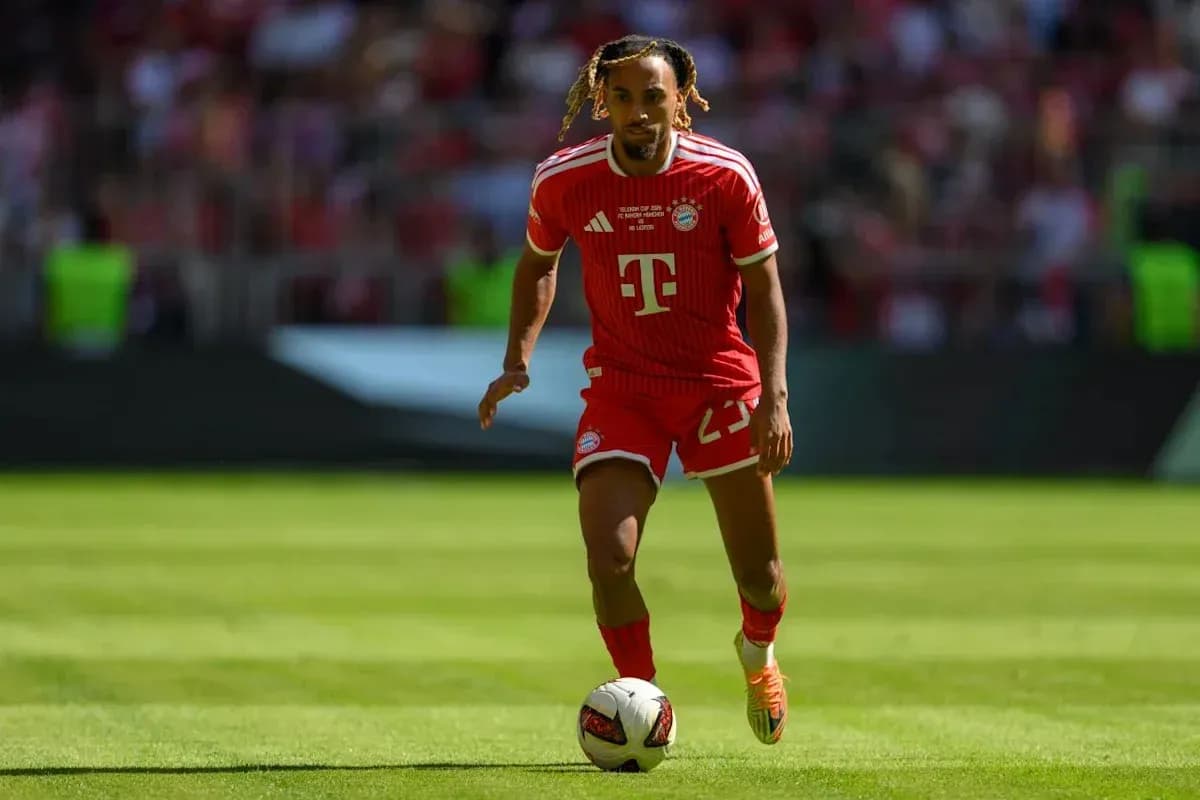 Player in Bayern Munich kit dribbling ball on field Player in Bayern Munich kit dribbling ball on field