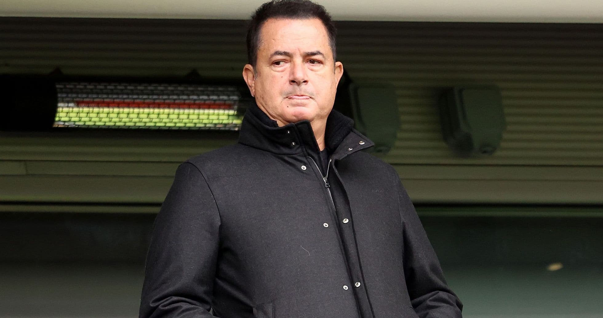 Person standing in a stadium wearing a black coat Person standing in a stadium wearing a black coat
