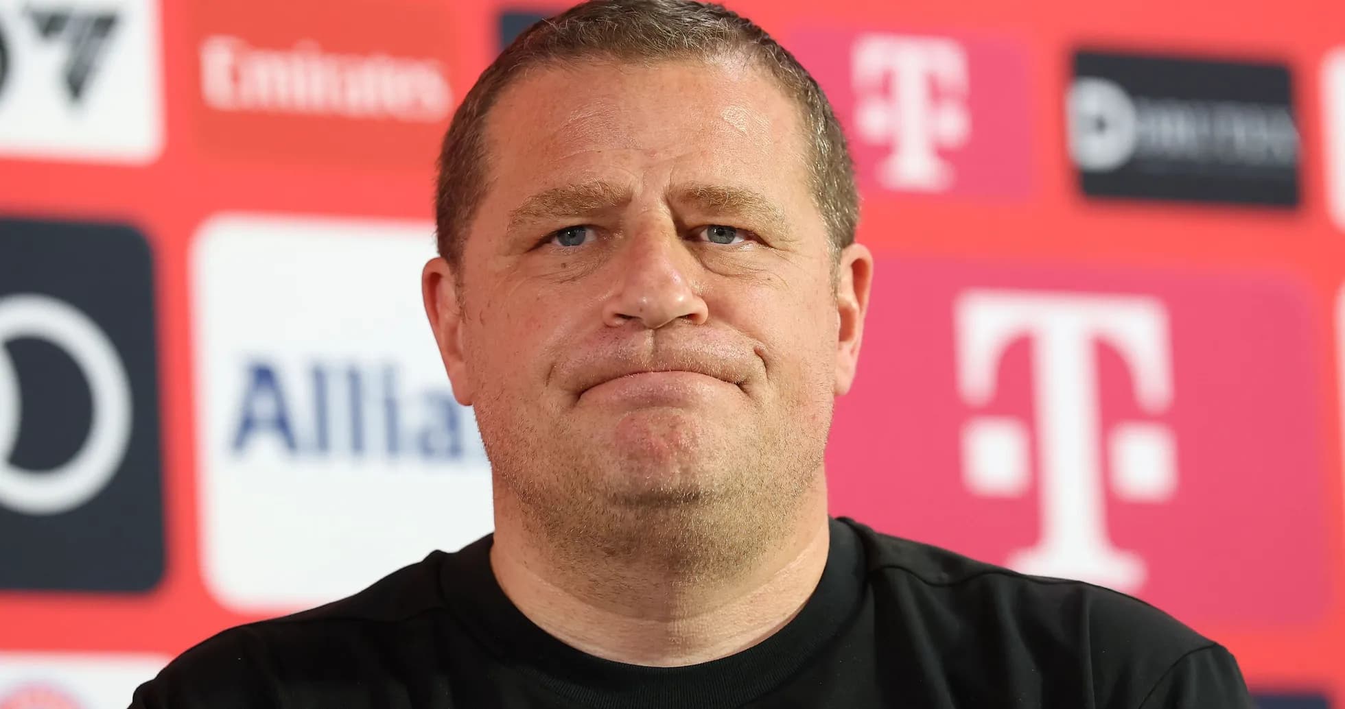 Man at press conference with team logos behind Man at press conference with team logos behind