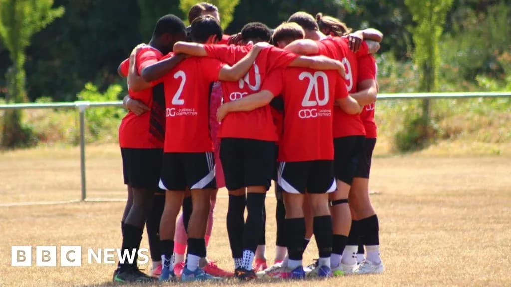 Team in red jerseys huddling on training field Team in red jerseys huddling on training field