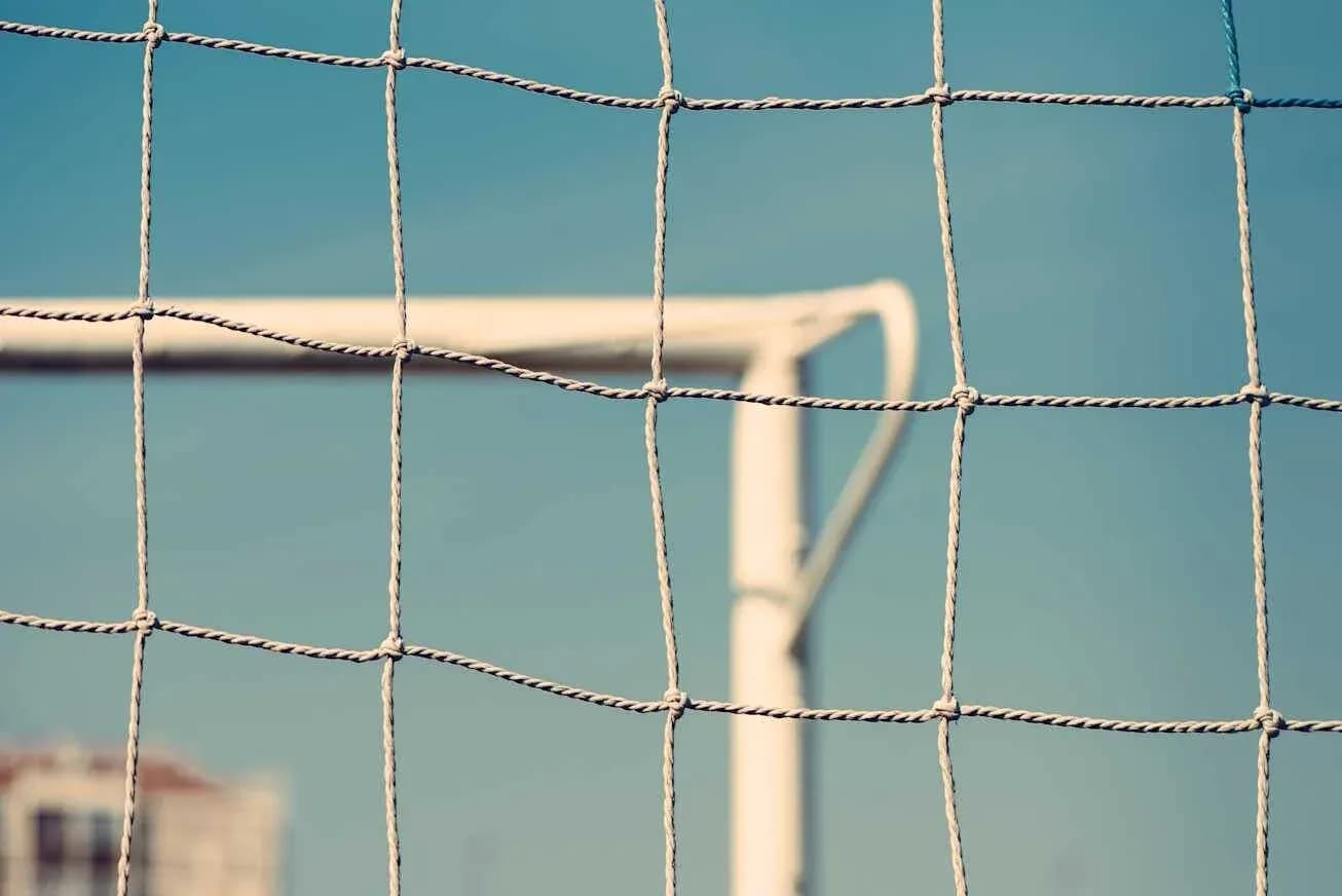 Close-up of a soccer goal net against blue sky Close-up of a soccer goal net against blue sky