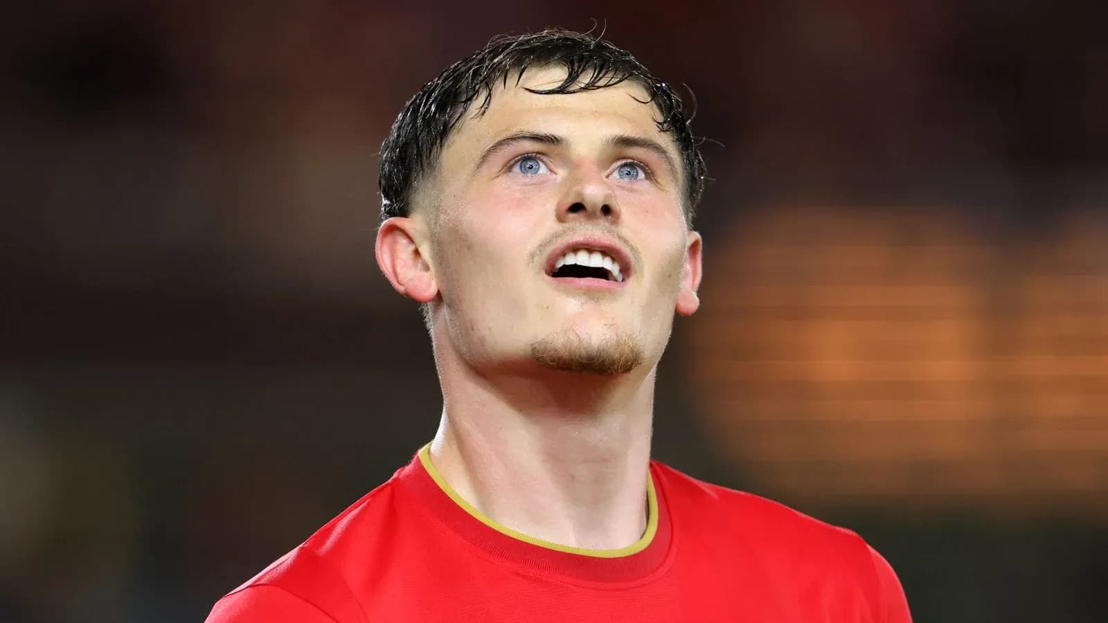 Player in red jersey looking upwards on field Player in red jersey looking upwards on field
