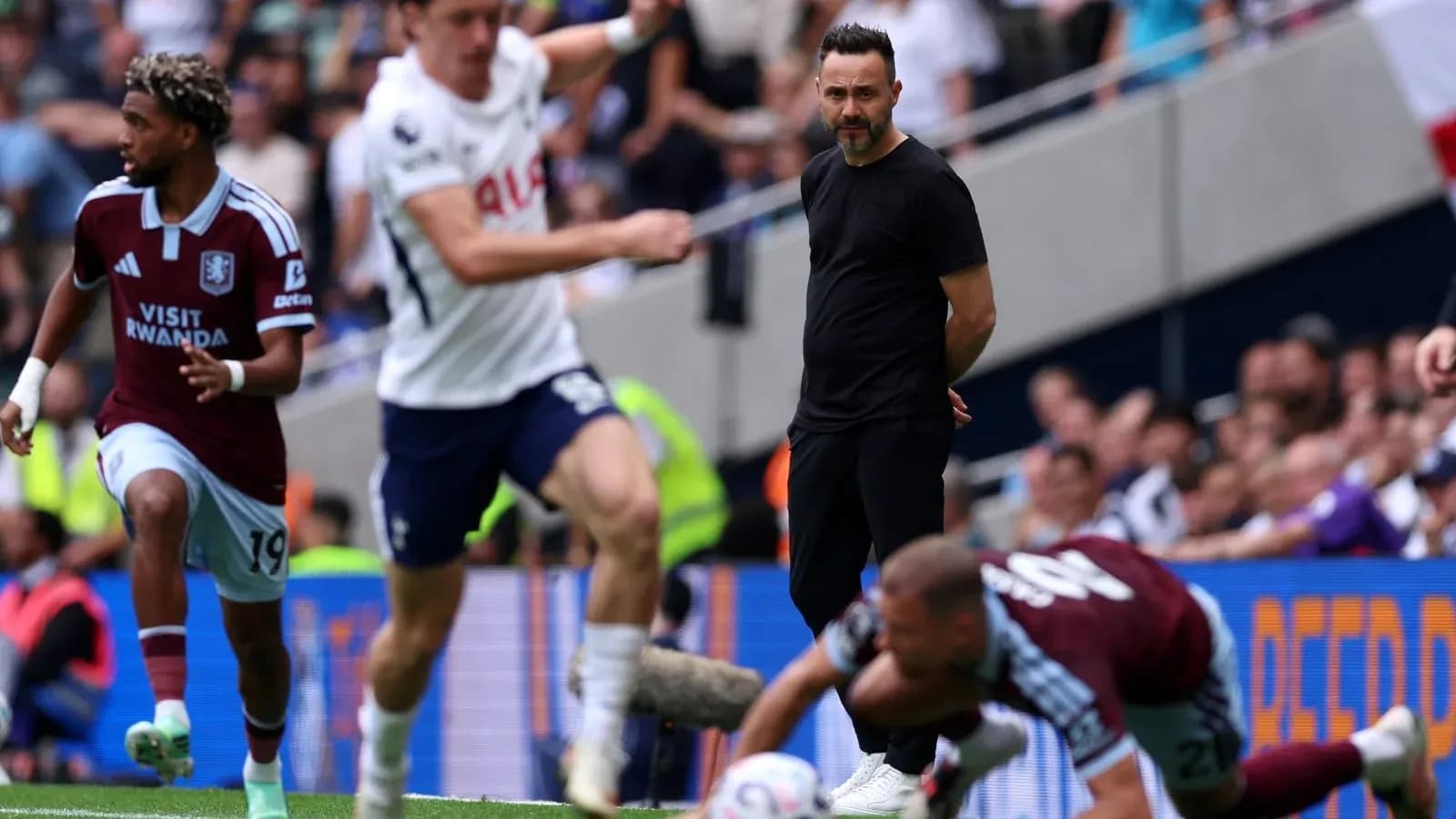 Aston Villa player dribbling past Tottenham coach during match Aston Villa player dribbling past Tottenham coach during match