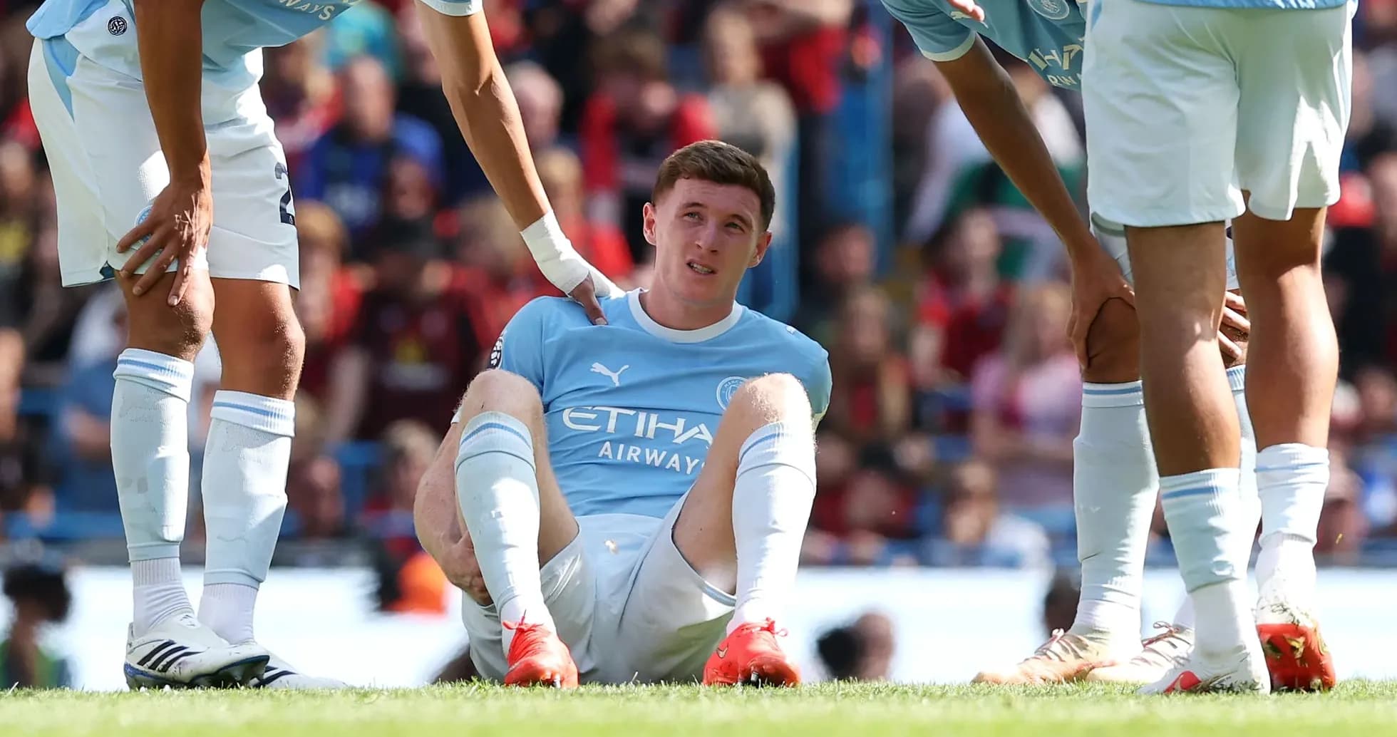 Player sitting on field receiving assistance from teammates Player sitting on field receiving assistance from teammates