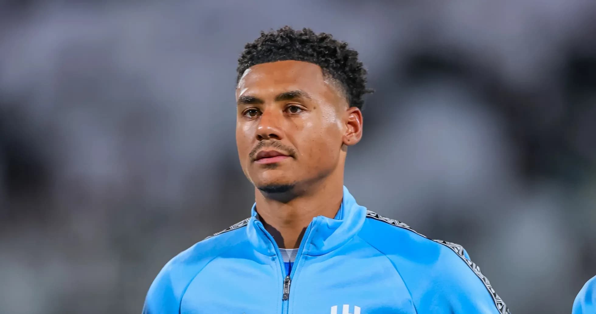Player wearing blue training jacket on field Player wearing blue training jacket on field