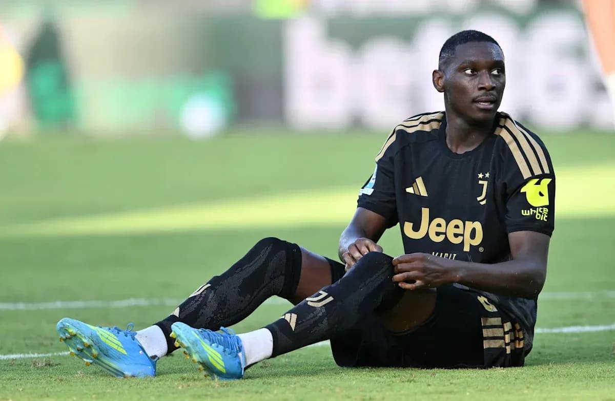 Juventus player sitting on the field, adjusting socks Juventus player sitting on the field, adjusting socks