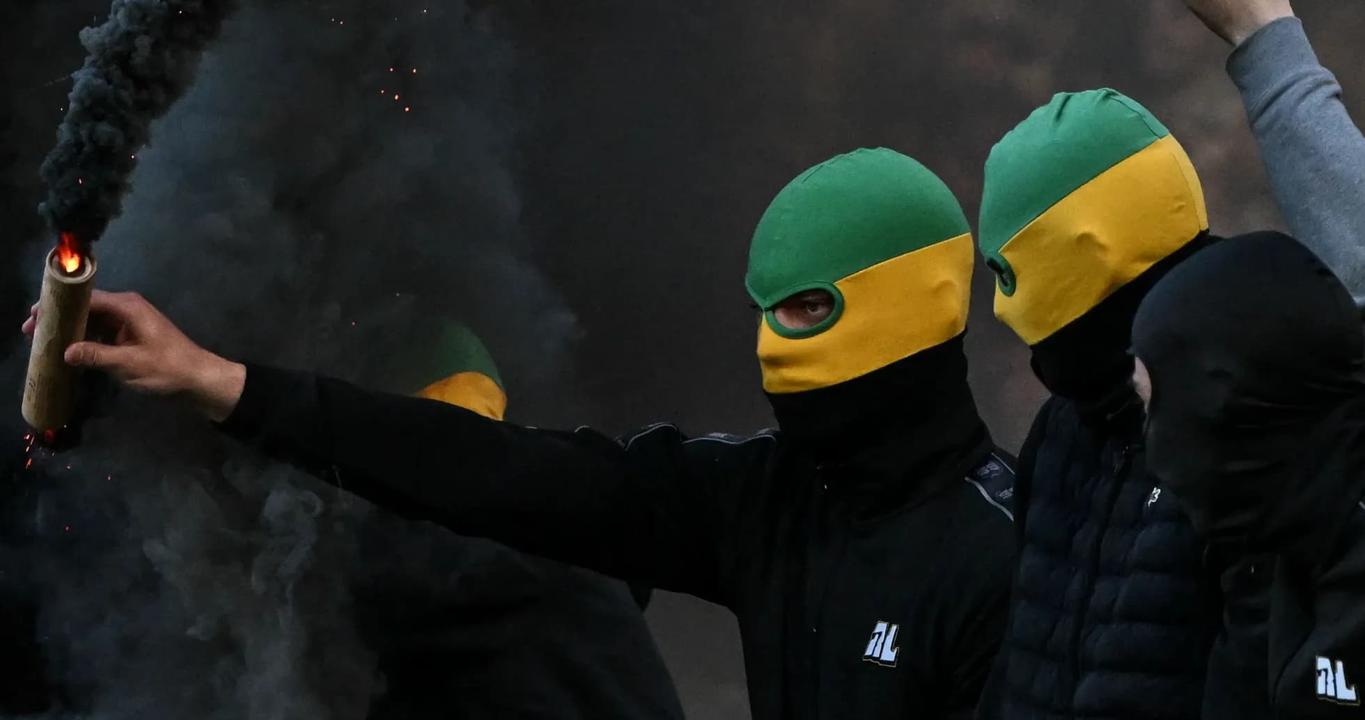 Masked individuals holding a flare in smoke Masked individuals holding a flare in smoke