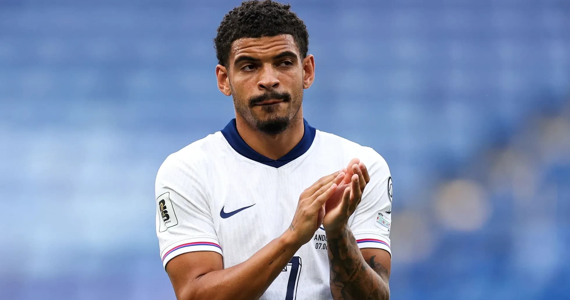 Player applauding in white team jersey on pitch Player applauding in white team jersey on pitch