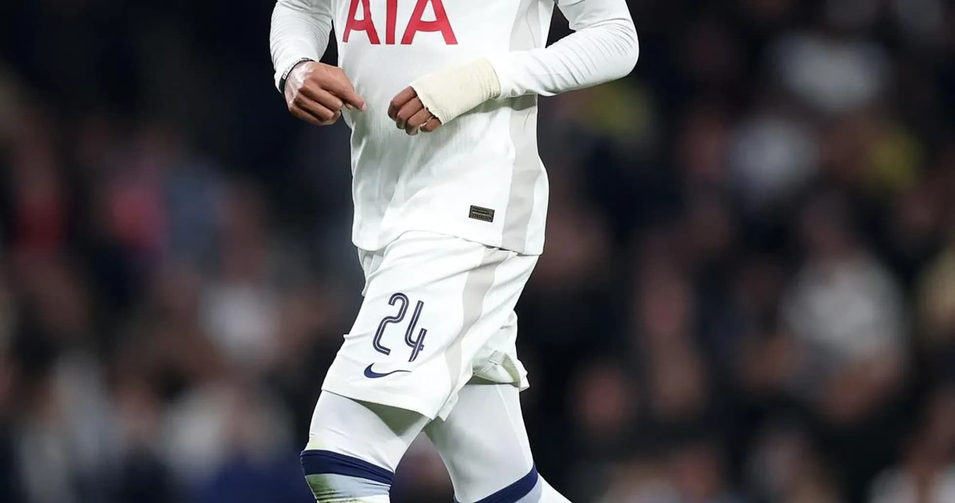 Player in Tottenham kit dribbling football on pitch Player in Tottenham kit dribbling football on pitch