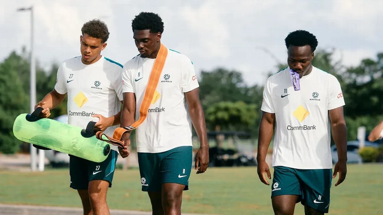 Three players walking with training equipment outdoors Three players walking with training equipment outdoors