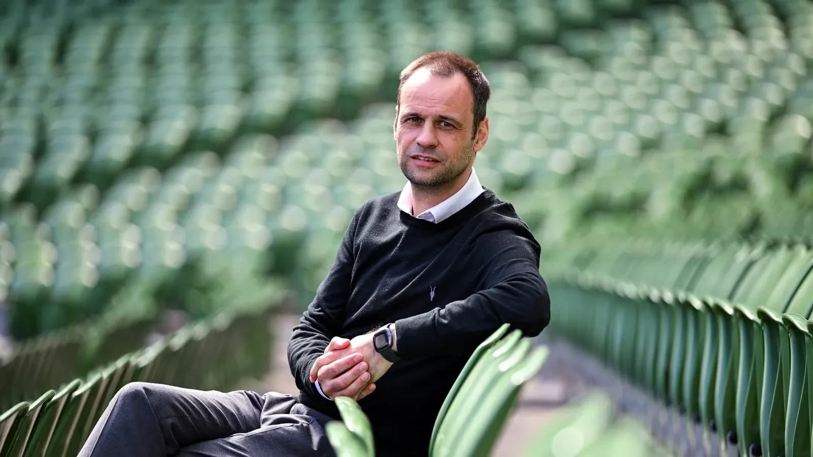 Man sitting on stadium seats, posing for photo Man sitting on stadium seats, posing for photo