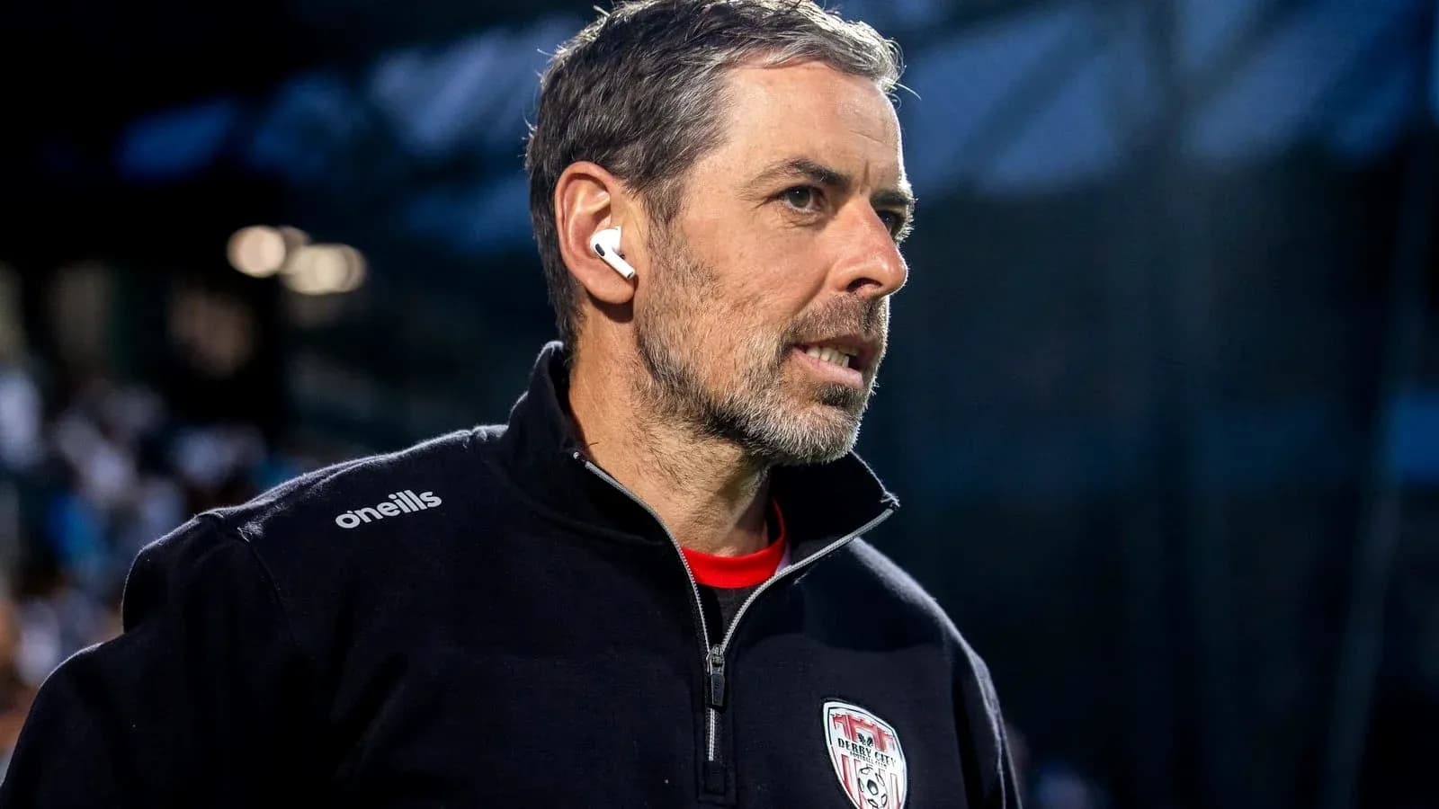 Coach wearing earbuds during match preparation Coach wearing earbuds during match preparation
