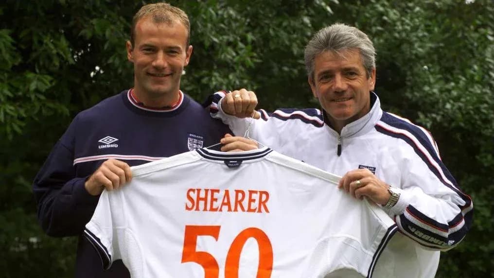 Two men holding England jersey with 'SHEARER 50' Two men holding England jersey with 'SHEARER 50'