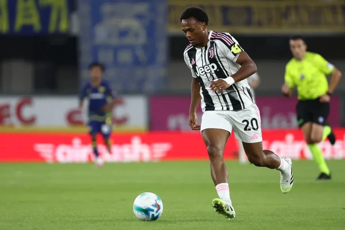 Player in Juventus kit dribbling ball on pitch Player in Juventus kit dribbling ball on pitch