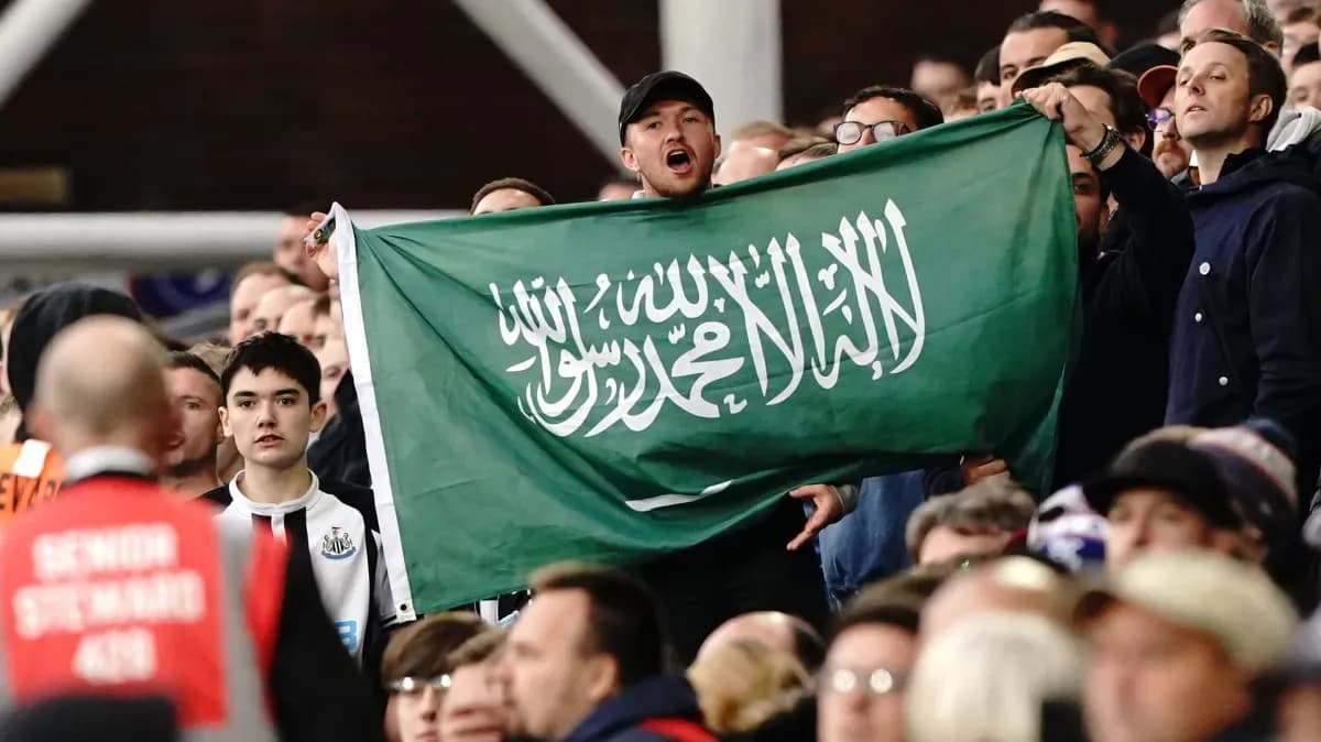 Fans holding Saudi Arabian flag in stadium crowd Fans holding Saudi Arabian flag in stadium crowd