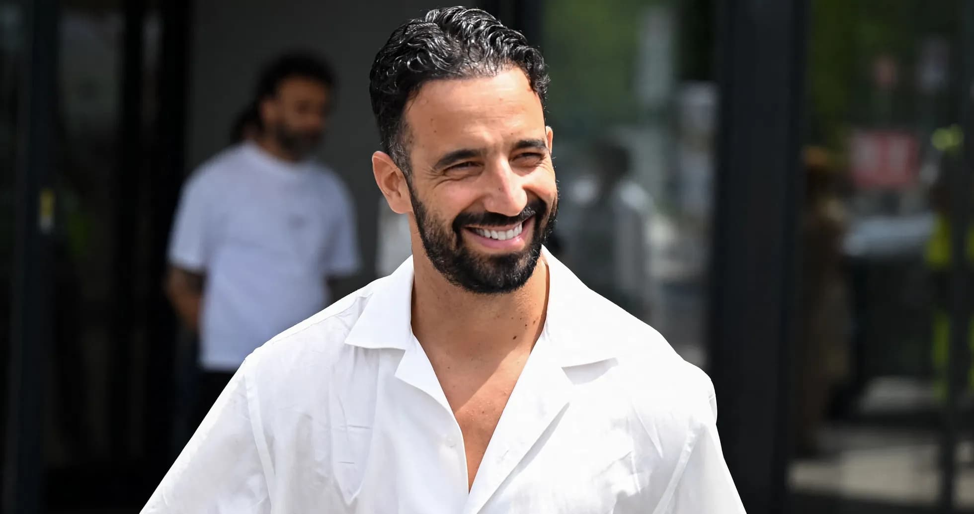 Man in white shirt smiling outside a building Man in white shirt smiling outside a building