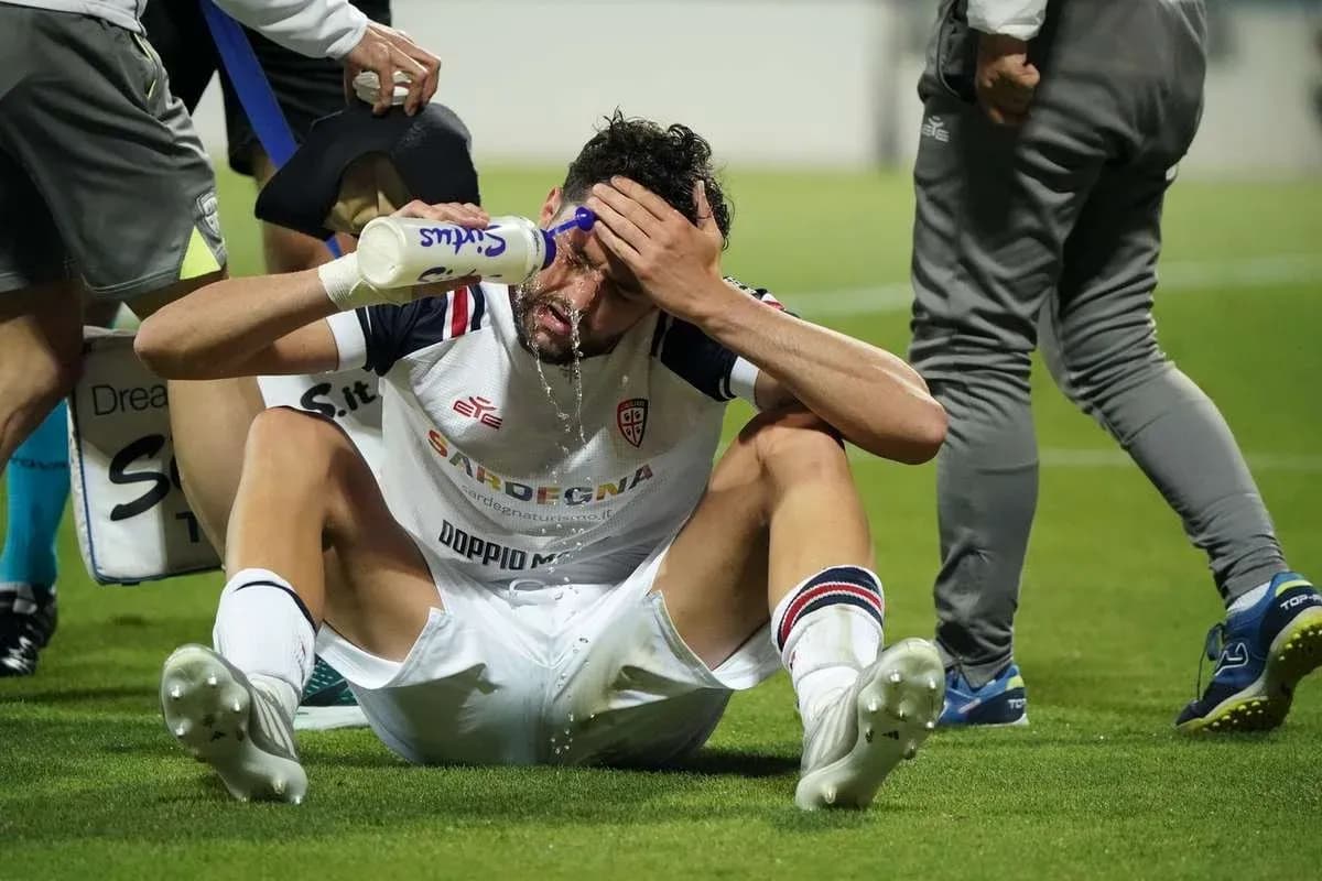 Player sitting on pitch pouring water on face Player sitting on pitch pouring water on face