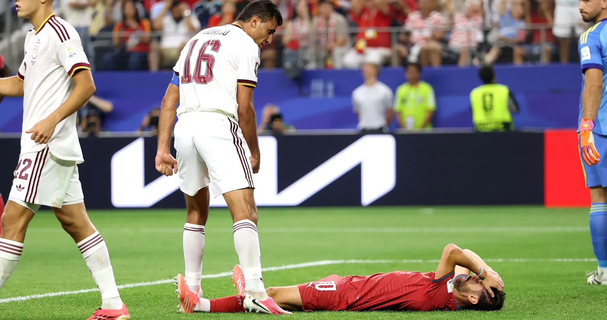Player lying on field with teammates nearby Player lying on field with teammates nearby