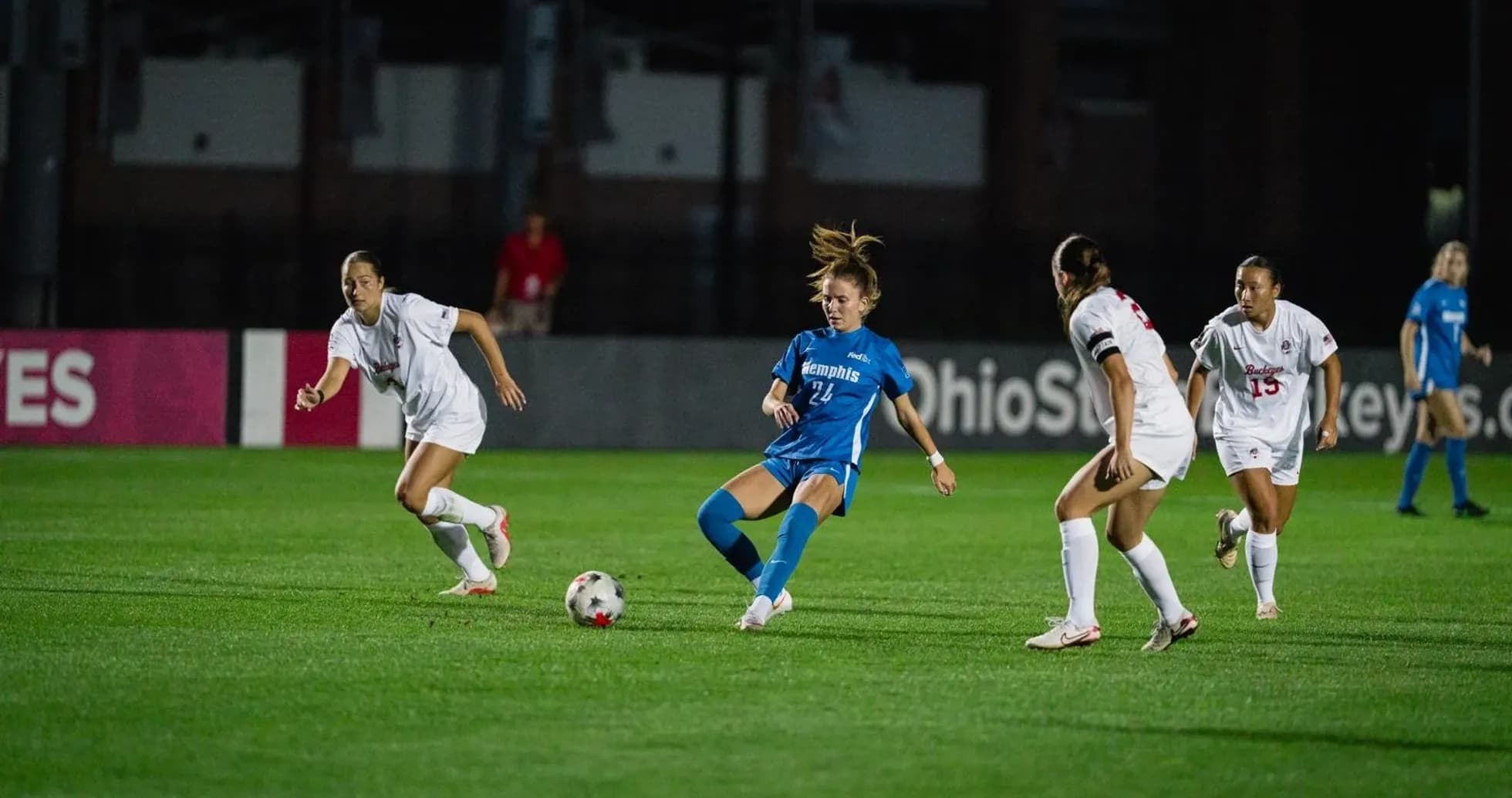 Player in blue dribbling past two defenders in white Player in blue dribbling past two defenders in white