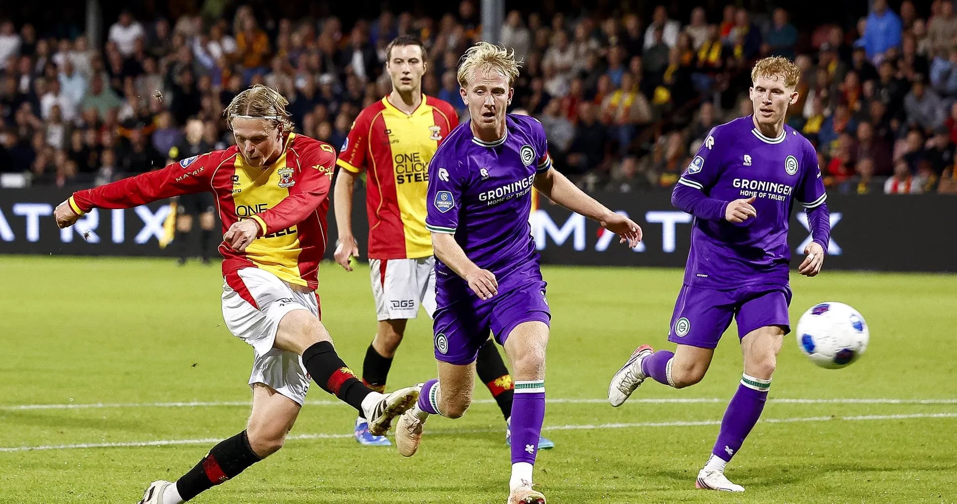 Player kicking ball with defenders nearby during match Player kicking ball with defenders nearby during match