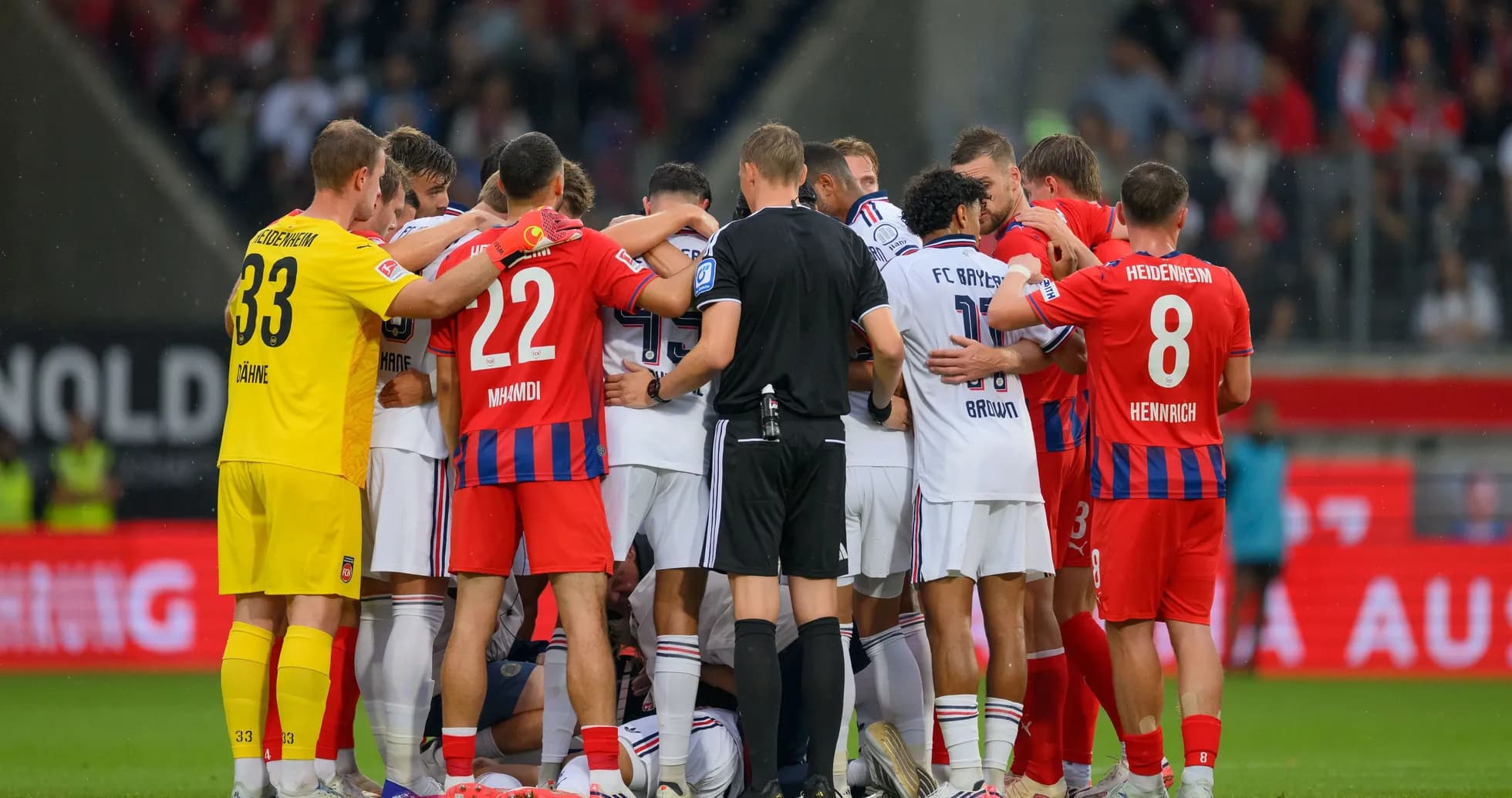 Players from both teams huddled together on pitch Players from both teams huddled together on pitch