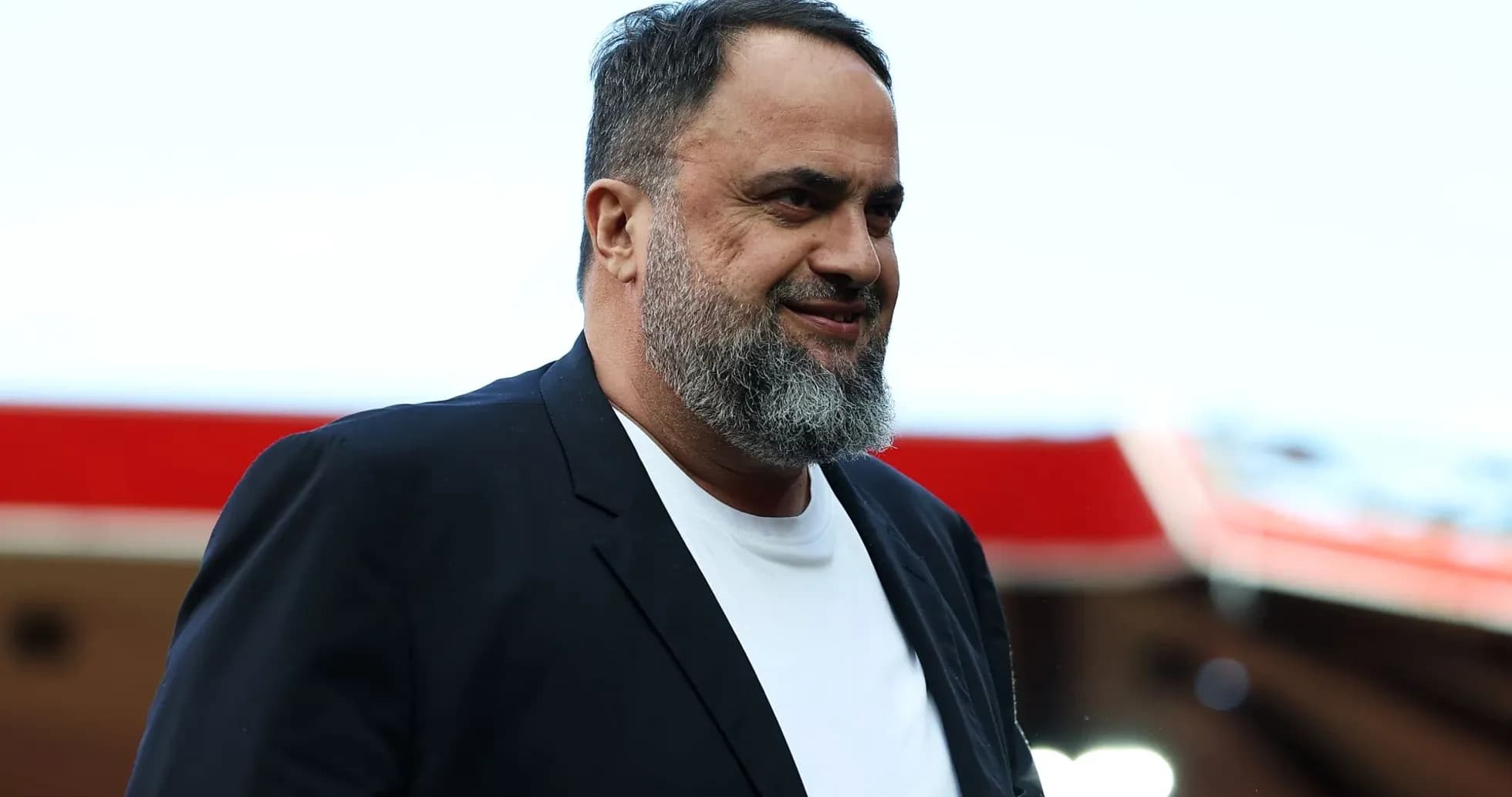 Man in black blazer smiling at stadium entrance Man in black blazer smiling at stadium entrance