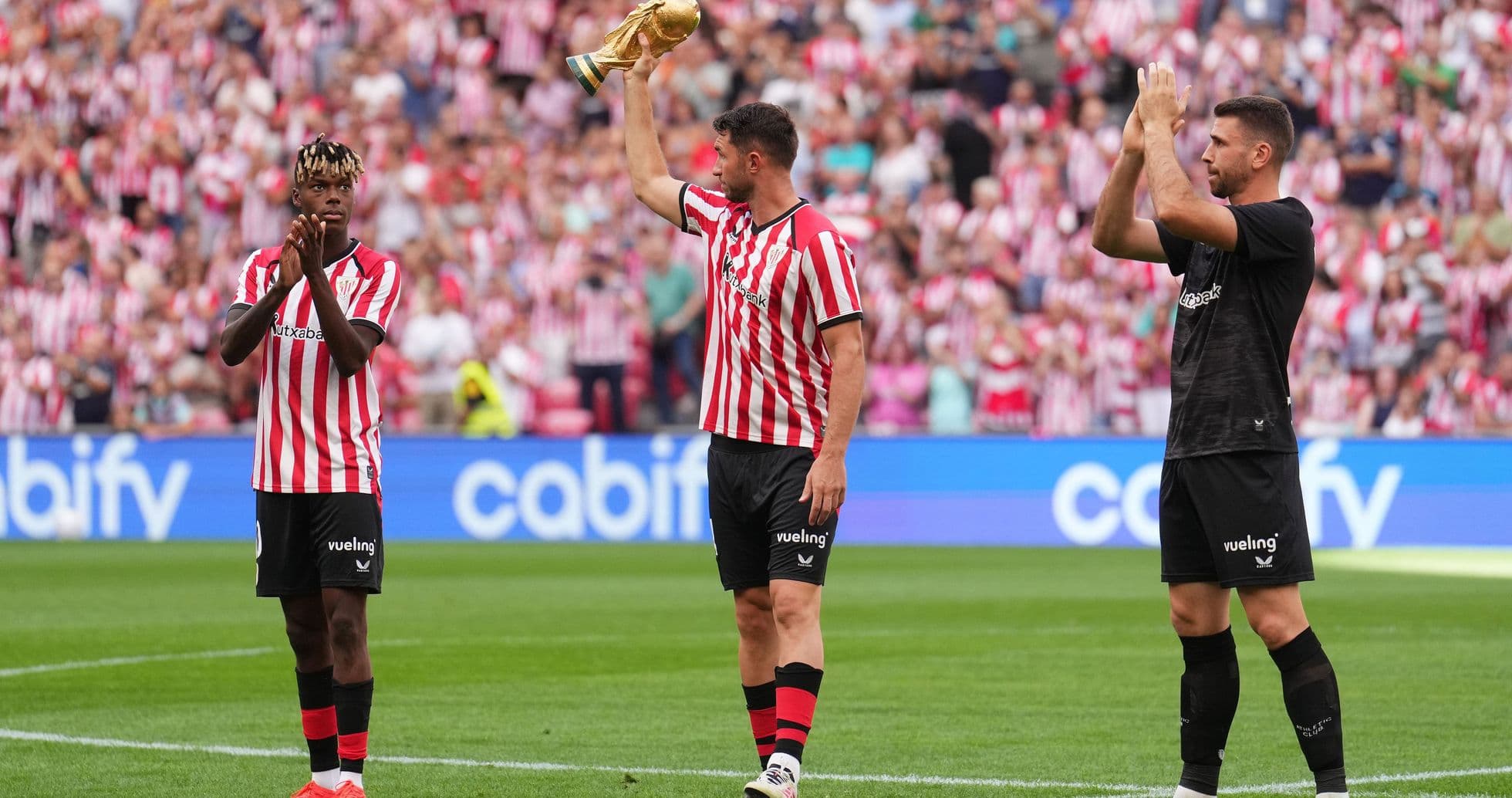 Players celebrating with trophy in front of fans Players celebrating with trophy in front of fans