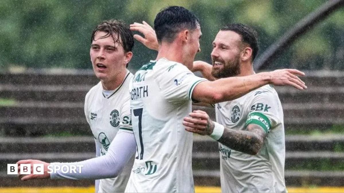 Players celebrating a goal in a rain-soaked match Players celebrating a goal in a rain-soaked match