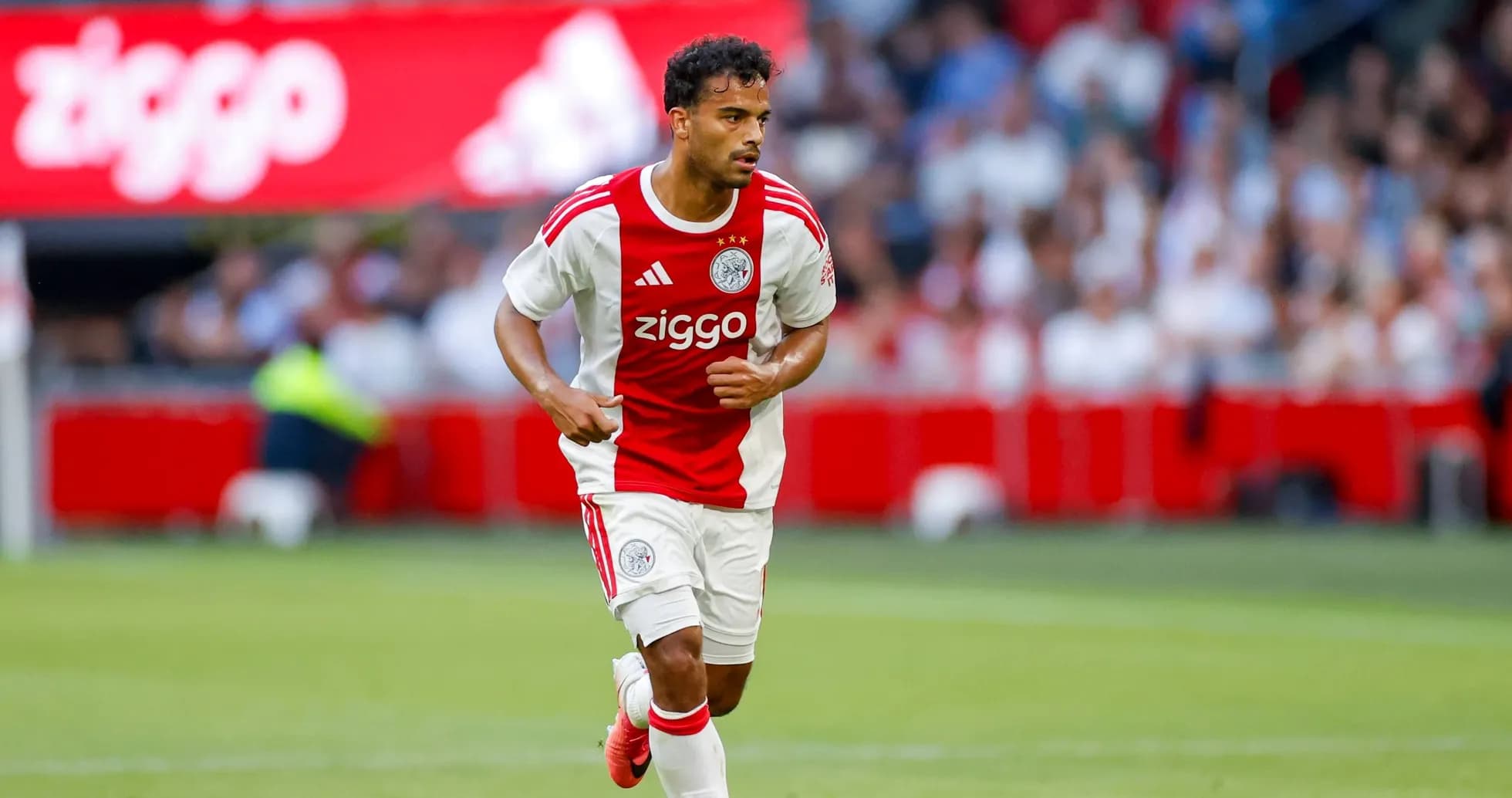 Player in Ajax kit running with ball on field Player in Ajax kit running with ball on field