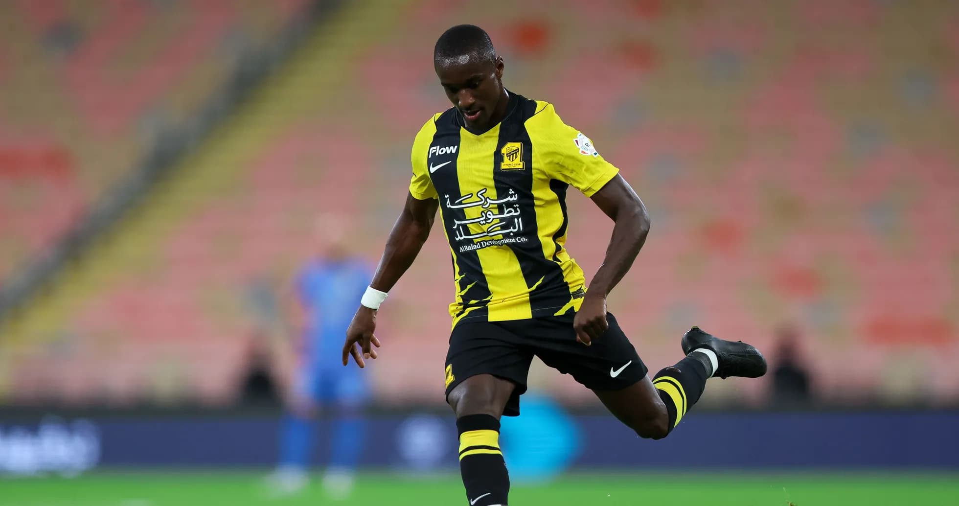 Player in yellow and black kit kicking a soccer ball Player in yellow and black kit kicking a soccer ball
