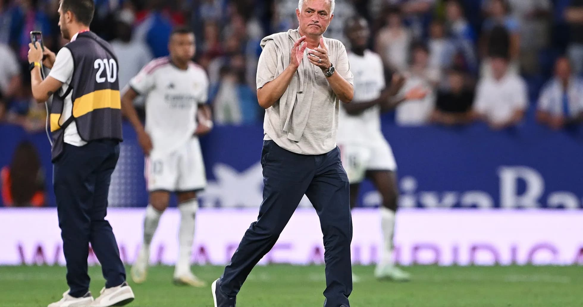 Manager clapping during match with players in background Manager clapping during match with players in background